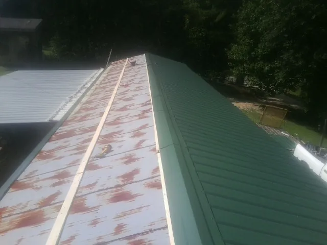 Old rusted panels beside newly installed green metal roofing — Wind Damage Roof Repair by Roofing Brothers in Mount Vernon