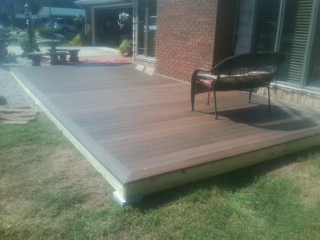 New wood deck and wicker chair beside a brick house in Mount Vernon