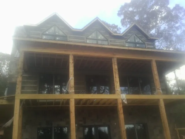 Dormers and porch framing on a large log home under construction — Roof Coating work by our crew in Mount Vernon