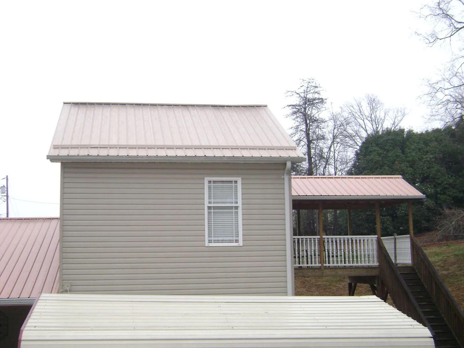 Tan metal roofs on a two story addition and attached porch, from a Roof Replacement job in Mount Vernon